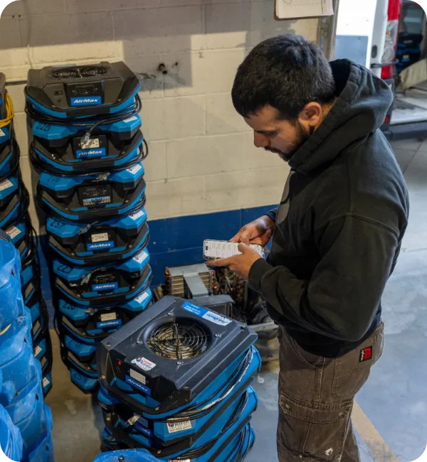 A technician using a phone beside restoration equipment.